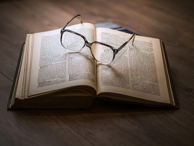 Okulary leżące na pożółkłej ze starości książce